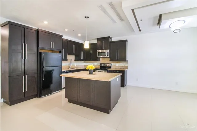 a kitchen with stainless steel appliances granite countertop a refrigerator a stove and a sink