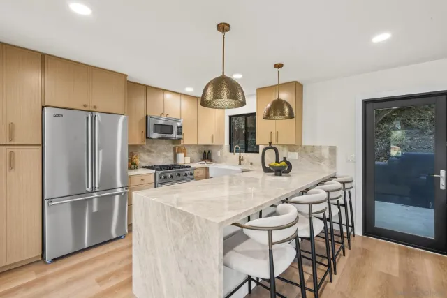 a kitchen with stainless steel appliances a dining table chairs stove refrigerator and wooden floor