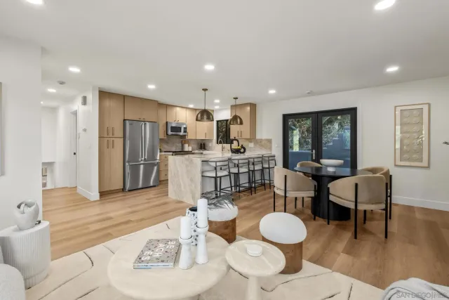 a living room with stainless steel appliances furniture a dining table and kitchen view