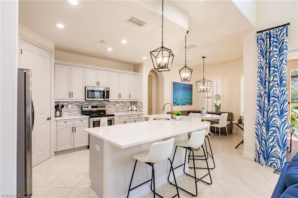 7797 Ashton Road Naples, FL 34113 - Photo 11 of 50 a kitchen with stainless steel appliances a table chairs stove and refrigerator