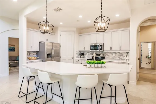 a kitchen with stainless steel appliances granite countertop a dining table chairs sink and refrigerator