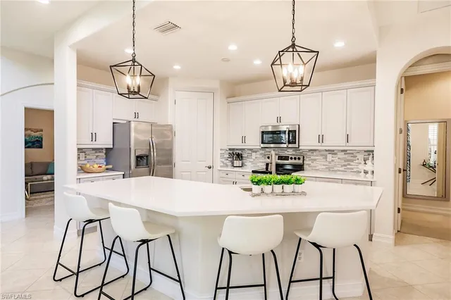 a kitchen with stainless steel appliances granite countertop a dining table chairs sink and refrigerator