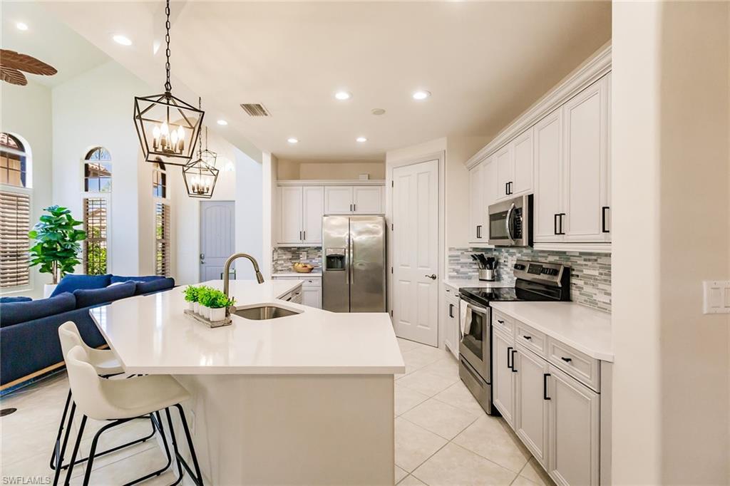 7797 Ashton Road Naples, FL 34113 - Photo 13 of 50 a kitchen with stainless steel appliances granite countertop a dining table chairs and a refrigerator