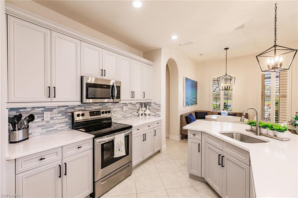 7797 Ashton Road Naples, FL 34113 - Photo 14 of 50 a kitchen with white cabinets and white appliances