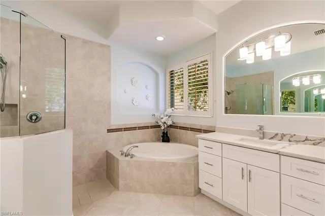 a bathroom with a granite countertop sink a large mirror a shower and a bathtub
