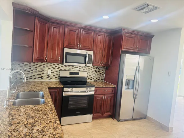 a kitchen with stainless steel appliances granite countertop a refrigerator stove and sink