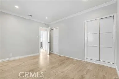 an empty room with wooden floor closet and windows