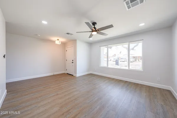 an empty room with wooden floor and windows