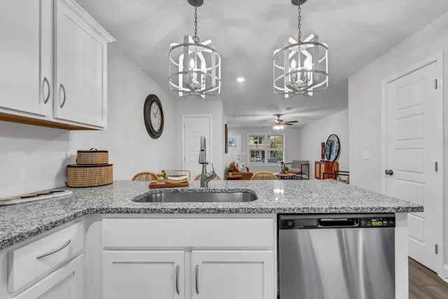 a very nice looking kitchen with granite countertop a white cabinets