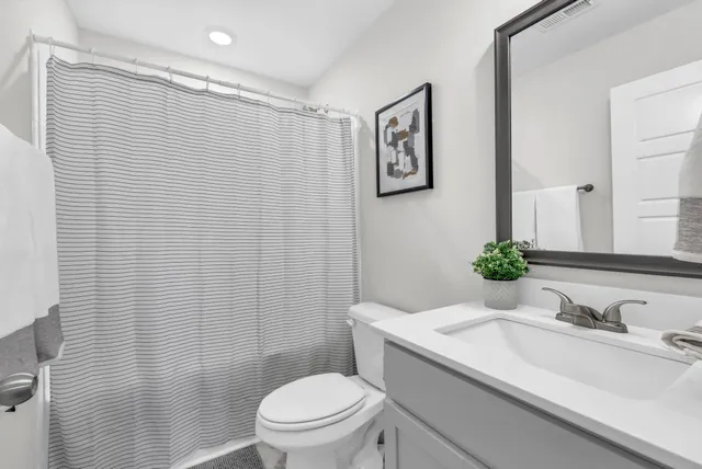 a bathroom with a granite countertop sink mirror vanity and toilet