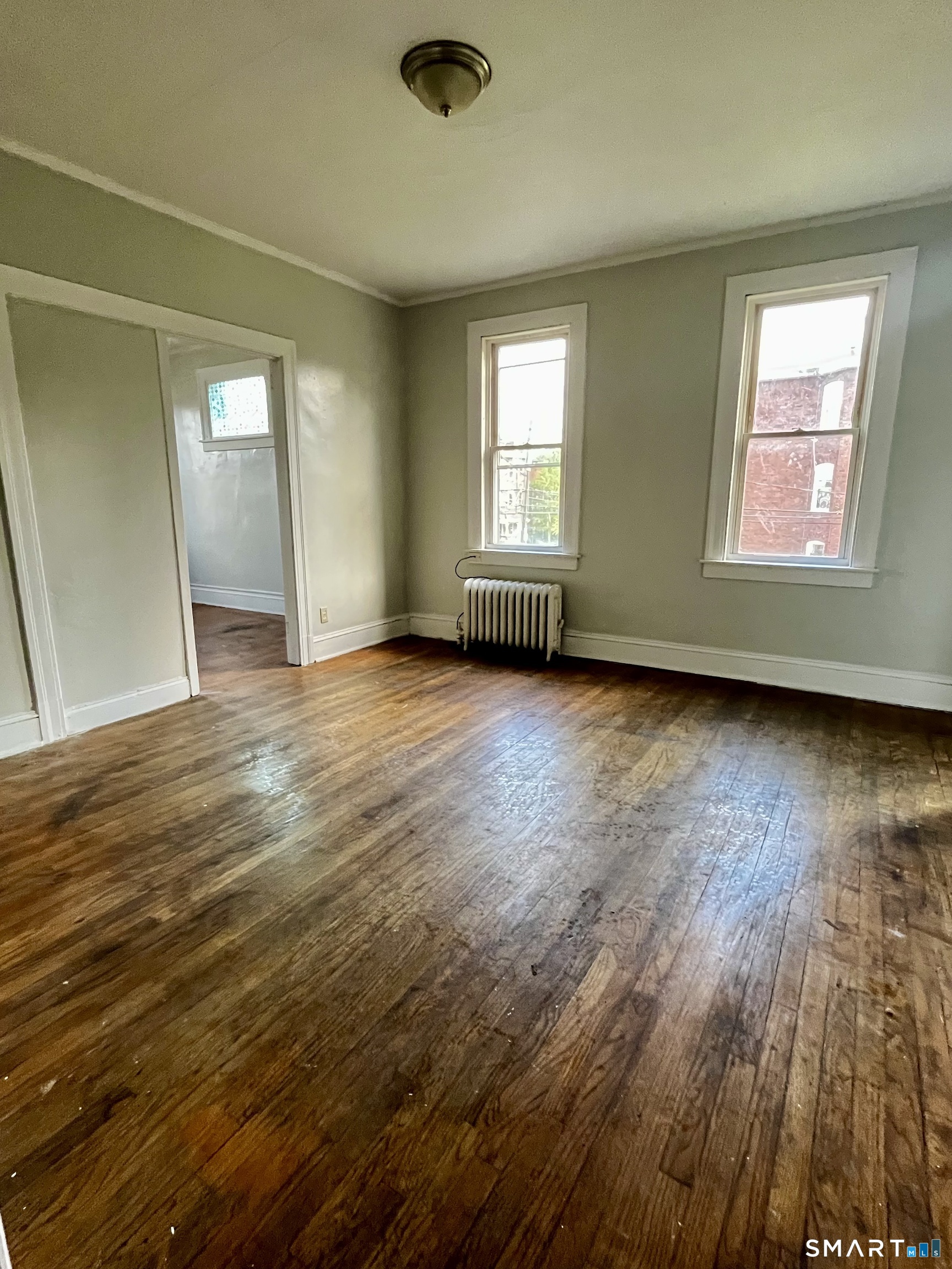 143 Putnam Street, Unit 2S Hartford, CT 06106 - Photo 8 of 9 an empty room with wooden floor and windows