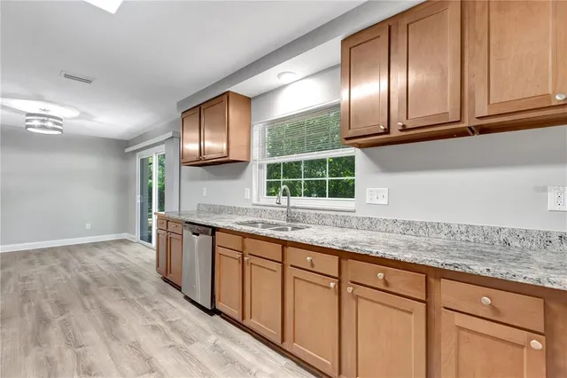 a kitchen with granite countertop stainless steel appliances sink stove and cabinets