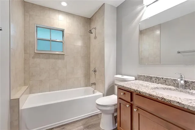 a bathroom with a granite countertop sink a toilet and bathtub