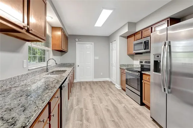a kitchen with kitchen island granite countertop a sink appliances cabinets and counter space