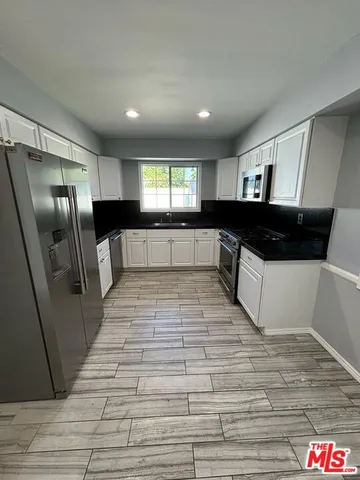a large white kitchen with stainless steel appliances granite countertop a refrigerator and a stove