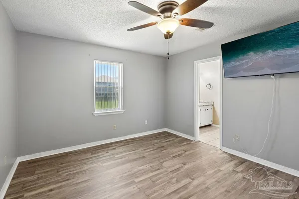 an empty room with wooden floor chandelier fan and windows