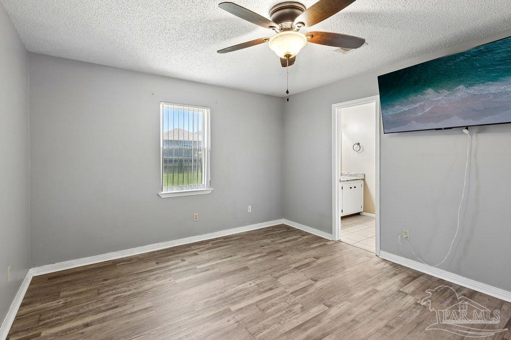 2329 Ryale Road Cantonment, FL 32533 - Photo 6 of 31 an empty room with wooden floor chandelier fan and windows