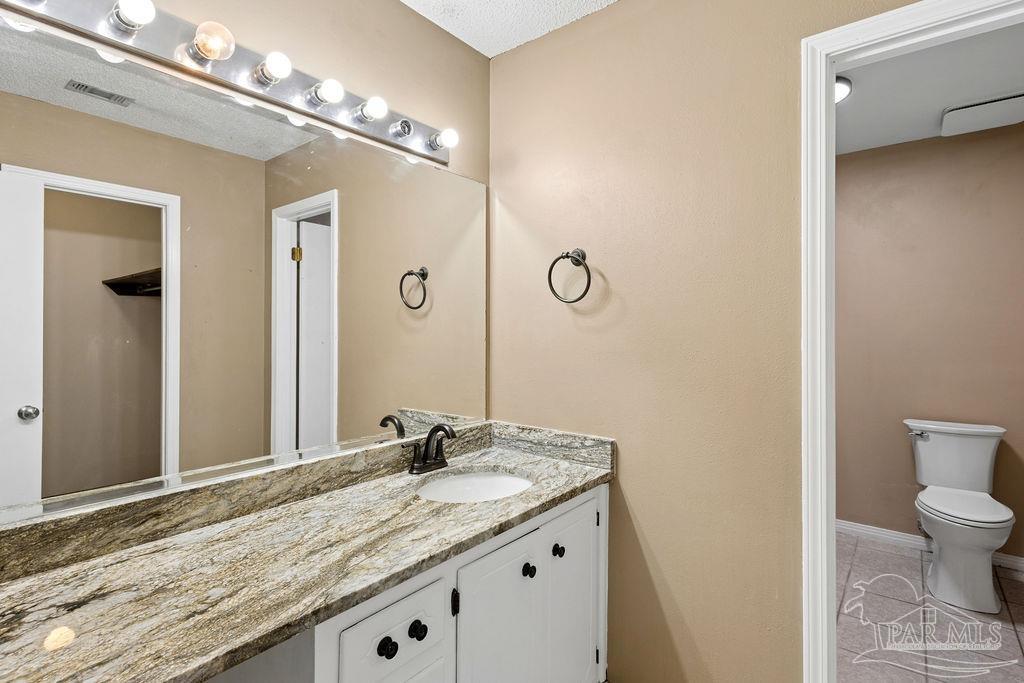 2329 Ryale Road Cantonment, FL 32533 - Photo 7 of 31 a bathroom with a granite countertop sink a toilet and a mirror