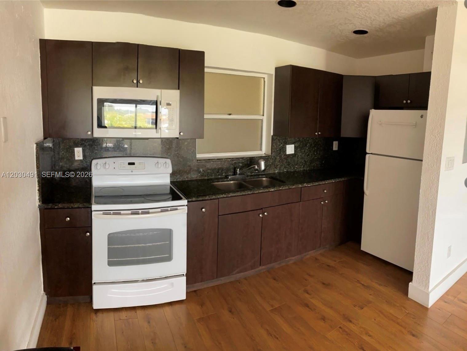 7410 Southwest 82nd Street, Unit K401 Miami, FL 33143 - Photo 2 of 5 a kitchen with a refrigerator sink and wooden cabinets