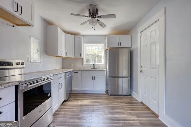 a kitchen with stainless steel appliances a stove a refrigerator and a sink with wooden floor