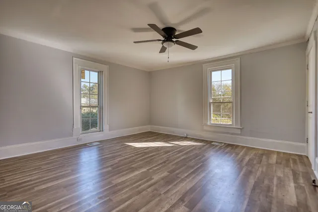 a view of empty room with wooden floor and fan