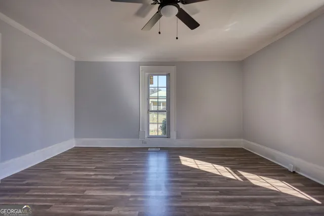 a view of empty room with wooden floor and fan