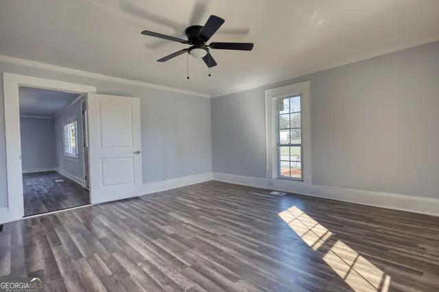 a view of empty room with wooden floor and fan