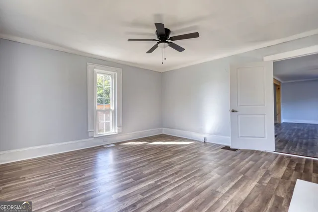 a view of empty room with wooden floor and fan