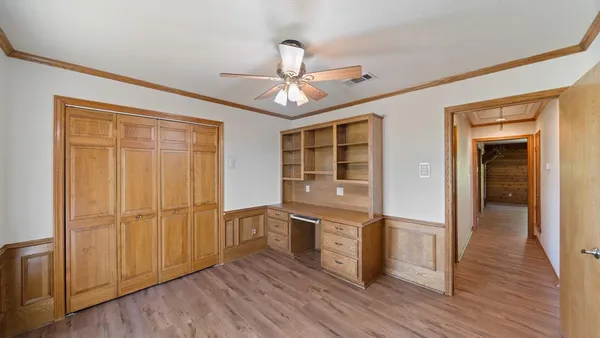 an empty room with wooden floor cabinet and windows
