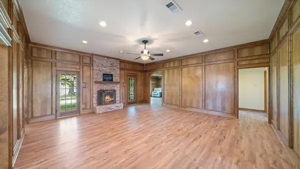 an empty room with wooden floor fireplace and windows