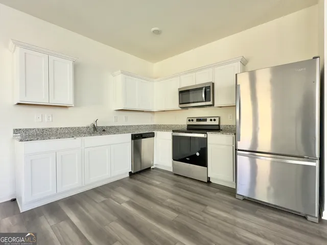 a kitchen with granite countertop white cabinets and stainless steel appliances