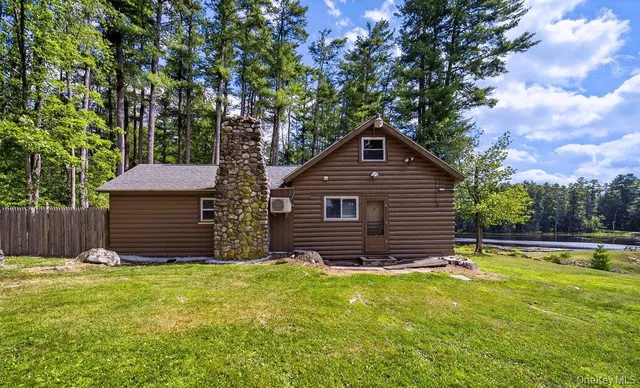 a front view of house with yard and trees in the background