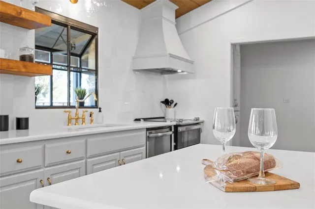 a kitchen with white cabinets a sink dishwasher and a stove with wooden floor