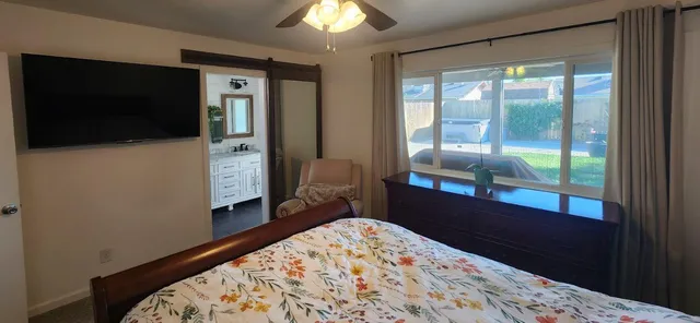 a bedroom with a bed and a flat tv screen next to a window