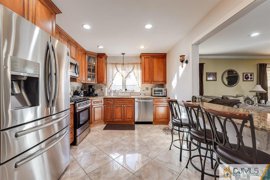 5 Starkin Road East Brunswick, NJ 08850 - Photo 5 of 34 a kitchen with stainless steel appliances kitchen island granite countertop a refrigerator a stove a sink dishwasher with a dining table and chairs