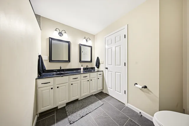 a spacious bathroom with a double vanity sink a mirror and a bathtub