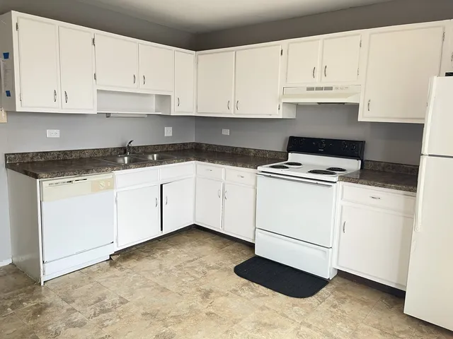 a kitchen with granite countertop white cabinets and white appliances