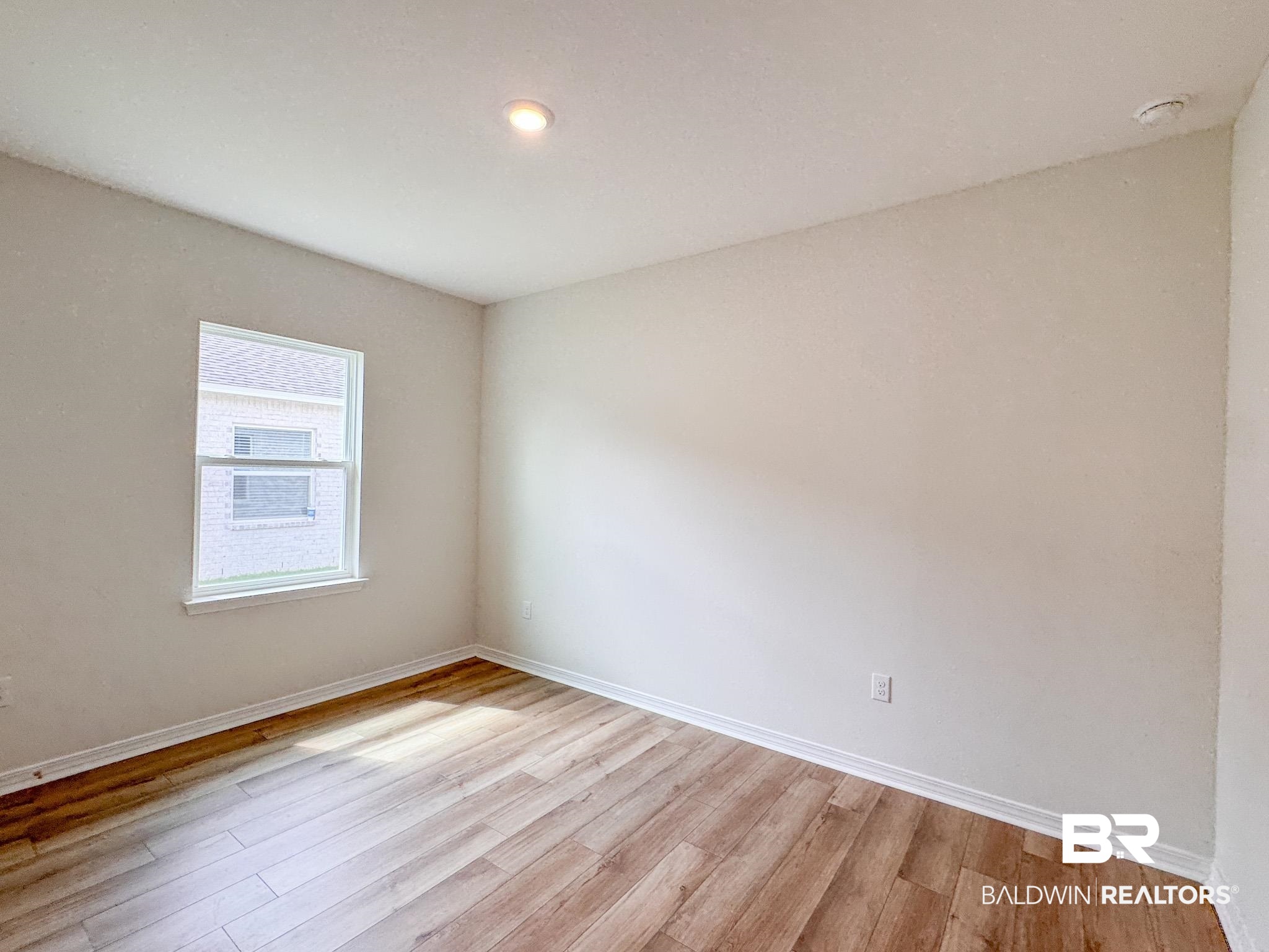 18151 Kent Circle Foley, AL 36535 - Photo 14 of 25 Room featuring wood-finish flooring, white baseboards, and a single window with white trim