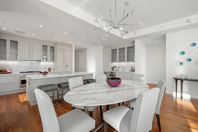 a kitchen with stainless steel appliances granite countertop a dining table chairs and white cabinets