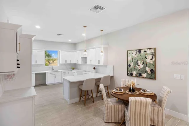 a open kitchen with stainless steel appliances kitchen island granite countertop a sink a stove a dining table and chairs