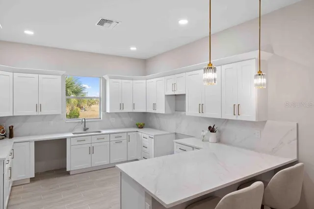 a kitchen with a sink a window and chairs