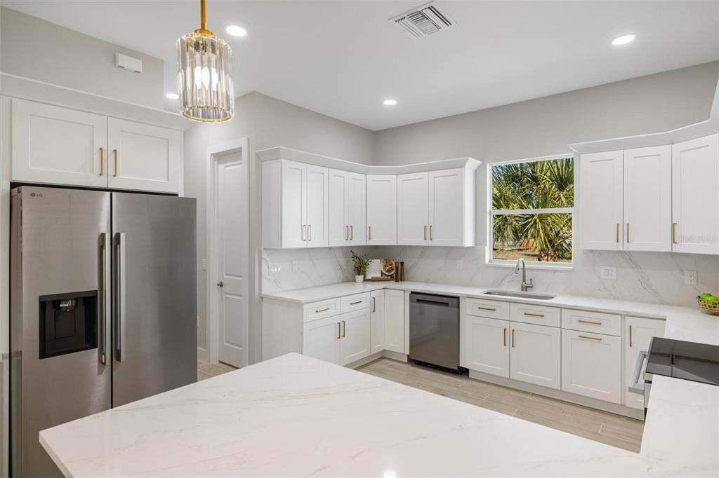 38 Lark Drive Placida, FL 33946 - Photo 16 of 46 a kitchen with a refrigerator a sink dishwasher a stove and white cabinets with wooden floor