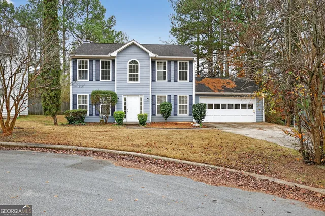 a view of a house with a yard and large trees