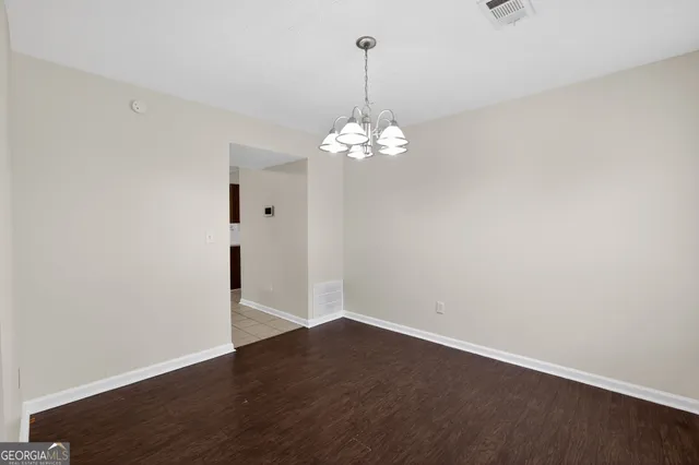 an empty room with wooden floor and chandelier