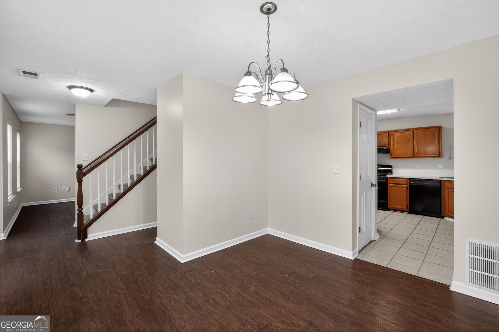 5635 Hunters Crossing Court Lithonia, GA 30038 - Photo 15 of 35 a view of a room with wooden floor staircase and a kitchen