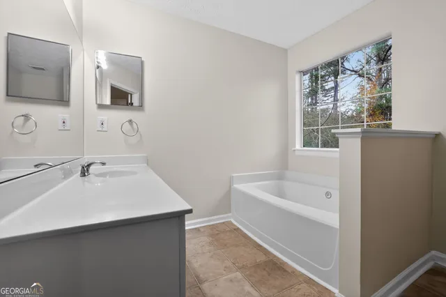 a bathroom with a tub a sink and mirror