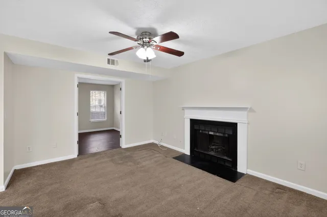 a view of an empty room with chandelier fan and fire place