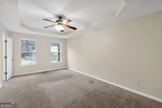 an empty room with windows and fan