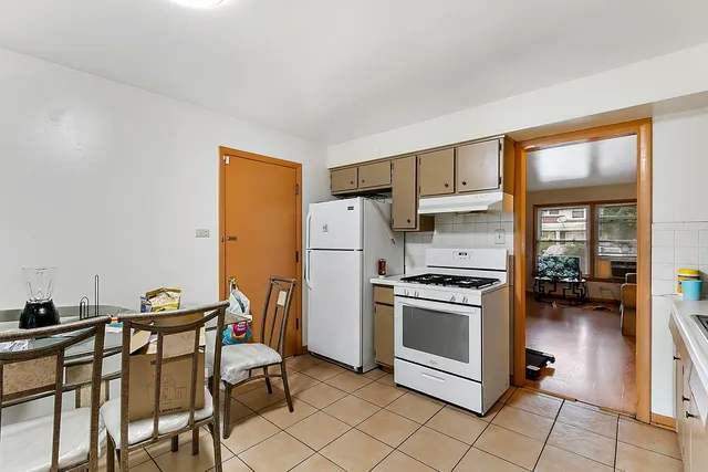 a kitchen with stainless steel appliances granite countertop a stove a refrigerator a dining table and chairs with wooden floor