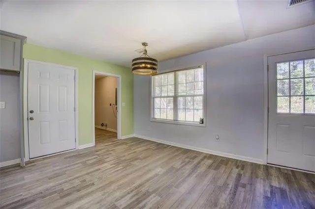 a view of kitchen and empty room with wooden floor